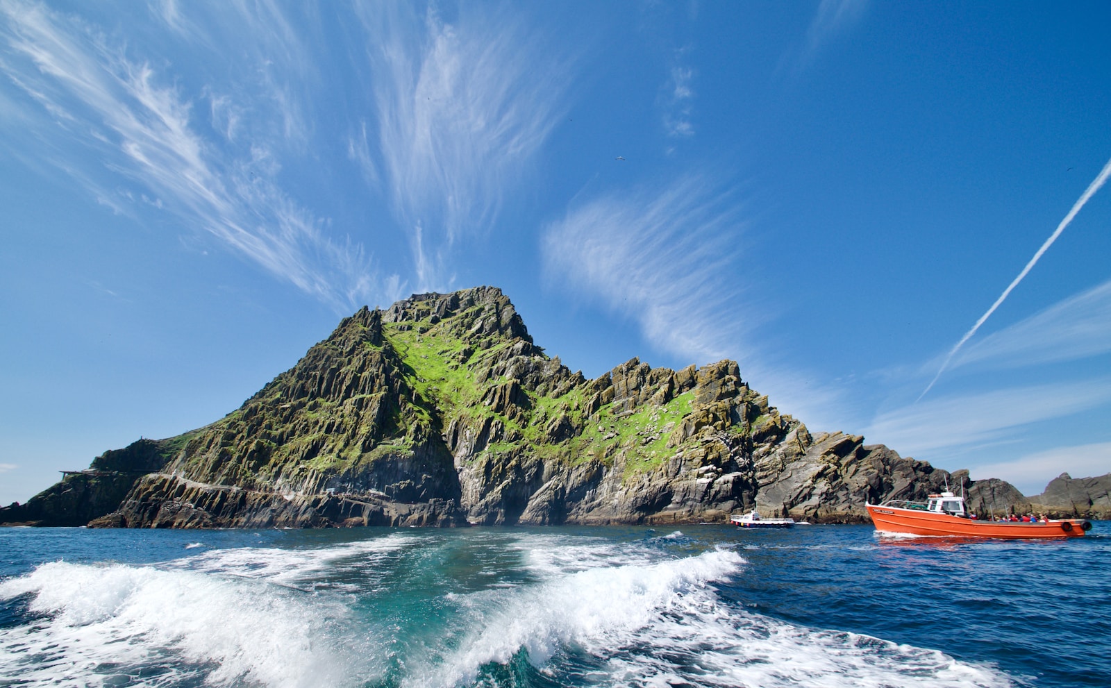 green and brown rock formation on sea under blue sky during daytime